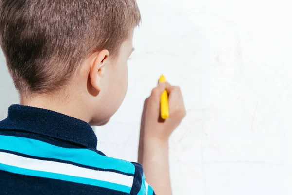 Beautiful child draws on the wall with colored pencils