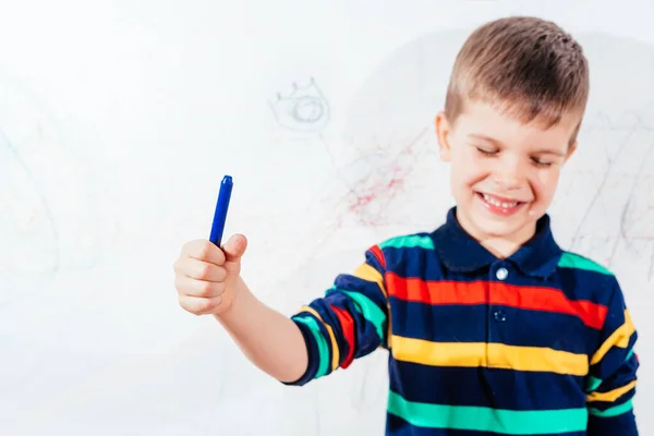 The child draws on the wall with colored chalk. The boy is engaged in creativity at home