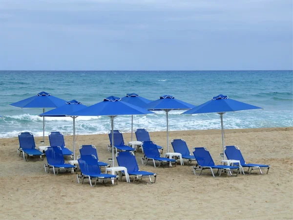 Kum üzerinde şemsiye ile mavi plaj sandalyeleri