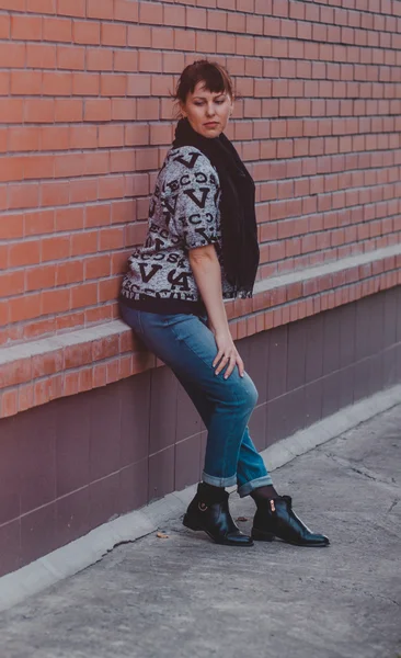 Young fashion beautiful girl posing on the street near brick wall background — Stock Photo, Image