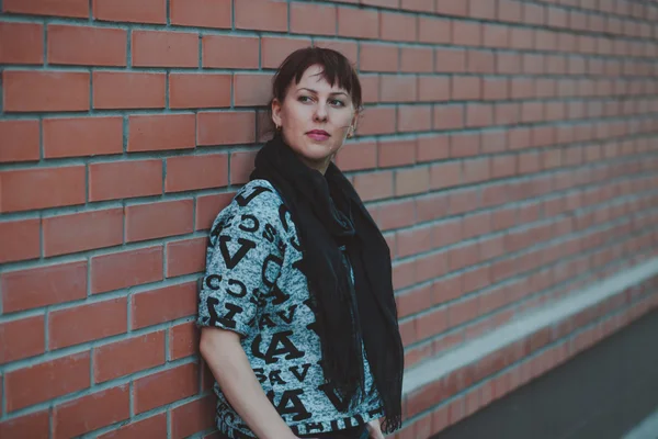 Jonge mode mooi meisje poseren op de straat in de buurt van bakstenen muur achtergrond — Stockfoto