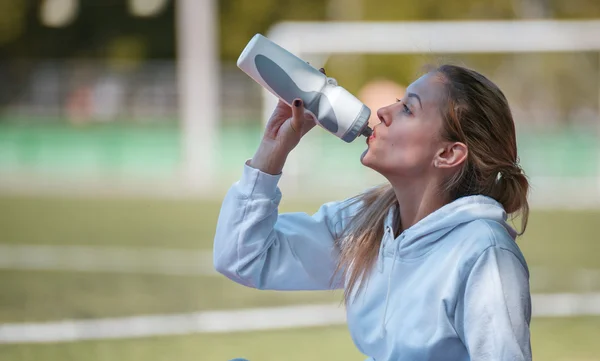 Young beautiful sportswoman resting after training. Woman drinking water — Stock Photo, Image