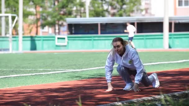 Молодая красавица делает упражнения на стадионе — стоковое видео