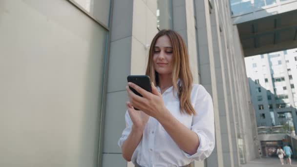 Una mujer atractiva miró al teléfono inteligente y sonrió mientras la cámara giraba y se movía a su alrededor. Primer plano de rotación completa de 360 grados. Tiro de arco de seguimiento — Vídeos de Stock