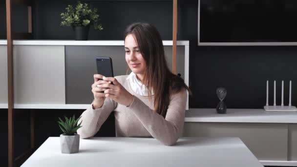 Millennial jeune femme passe du temps au bureau avec la technologie gadget cellulaire. Dame détendue en utilisant le téléphone intelligent surfer sur les médias sociaux, vérifier les nouvelles, jouer à des jeux mobiles ou envoyer des messages texte à moderne — Video