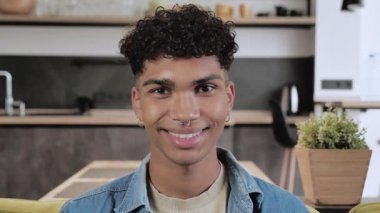 Evdeki kameraya bakan mutlu genç siyahi öğrenci, gülümseyen Afro-Amerikan adam çalışma alanında gülüyor, 4K portresini yakın çekiyoruz.