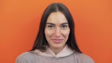 Utangaç insan ifadesi. Turuncu stüdyodaki utangaç kadın izole edilmiş. Utanç dolu bir kızın portresi..