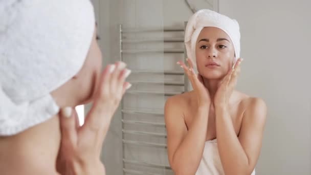 Ung kvinna tittar i spegeln applicerar kräm på ansikte och kropp och massage. Förhindra åldrandebegreppet 4k — Stockvideo