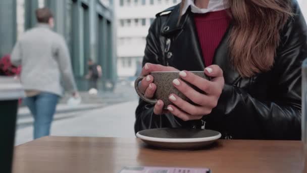 Primer plano de las manos femeninas beber chocolate caliente o café y relajarse en la cafetería. Atención de la salud, autenticidad, sentido del equilibrio y la calma en el contexto urbano 4k — Vídeo de stock
