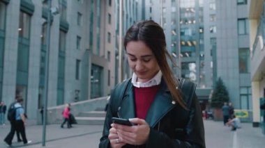 Bir iş merkezinin arka planında telefonu olan genç bir kadın. Çevrimiçi servis taksi siparişi mobil uygulama. 4k