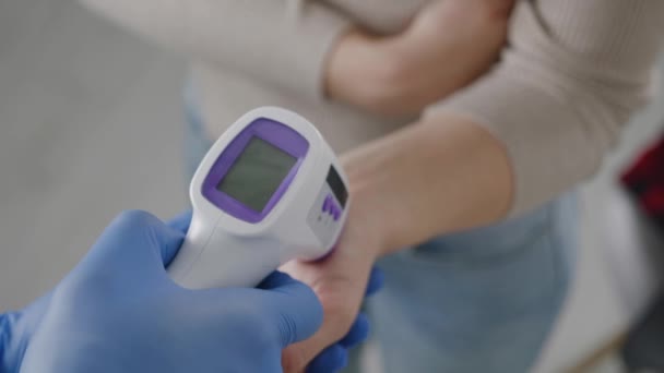 Dokter meet de temperatuur van zijn patiënt en toont de normale temperatuur op het display van een infrarood contactloze thermometer, patiënt concept — Stockvideo