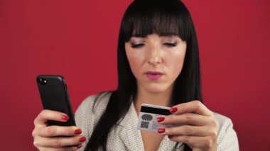 Akıllı telefon ve kredi kartı tutan genç bir bayan yakın plan ödemesini ya da hızlı bir uzaktan para transferini yapar. E-banka uygulaması ve kablosuz cihaz modern teknoloji kullanımı