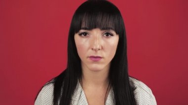 Beyaz gömlekli 30 'lu yaşlardaki genç bir kadının portresi stüdyoda kırmızı duvar arkasında izole edilmiş. İnsanların yaşam tarzı konsepti. Kamera kendini gösterip kim olduğumu soruyor. Hayır, ben değilim.