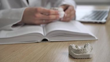 Alçıtaşı diş sağlığı ekipmanının arka planda anatomi kitabını okuyan kadın doktorla yakın plan görüntüsü. Genel uygulama kavramı
