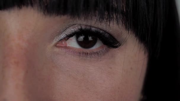 Vrouw van 30 jaar oud opent en sluit een donkerbruin oog — Stockvideo