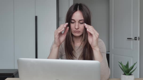 Unavená běloška pracuje na laptopu příliš dlouho. Krásná mladá tisíciletá žena sedící od počítače, přerušující práci a masírující spánky. Koncept únavy nebo bolesti hlavy. — Stock video
