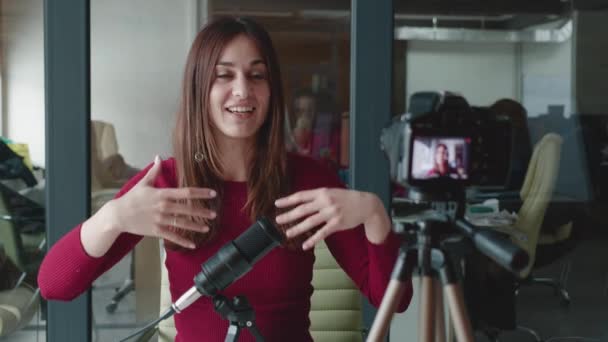 Молода жінка тисячоліття в бургундському светрі подкаст робить аудіо подкаст з її офісної студії. Вона надихає своєю промовою — стокове відео