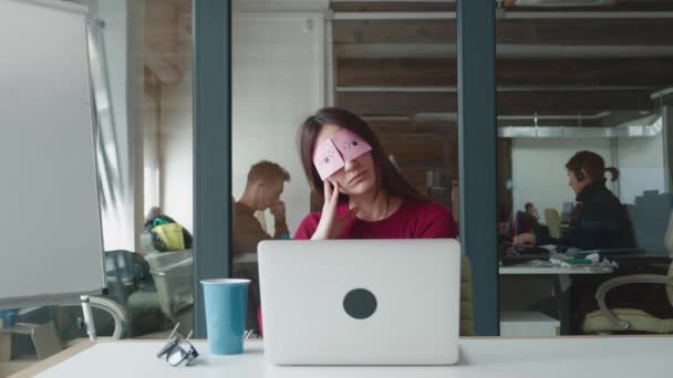 Beceriksiz kadın çalışanlar masasında oturan çıkartmalarla uyuyormuş gibi yapıyor. Tembel ofis çalışanı iş yerinde kestiriyor. Gözleri yapışkan notlarla örtüyor.. — Stok video