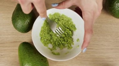 Avokadoyu çatalla kaseye ezmek. Vejetaryen avokado sosu hazırlıyorum. Sağlıklı yemek pişirmek. Üst görünüm