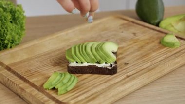 Avokado tostu. Erkek şef krem peynirli tostun üzerine dilimlenmiş avokado koydu.