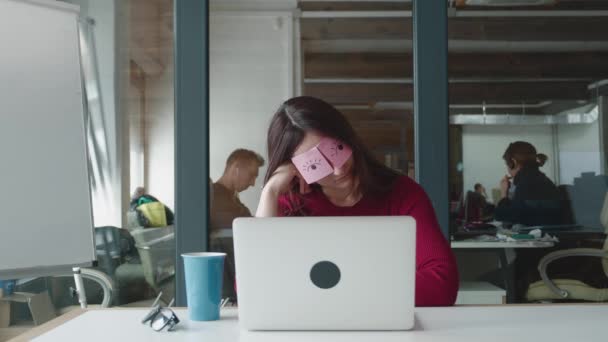 Divertido procrastinación mujer de negocios siesta en el lugar de trabajo cubriendo los ojos con notas adhesivas. — Vídeo de stock