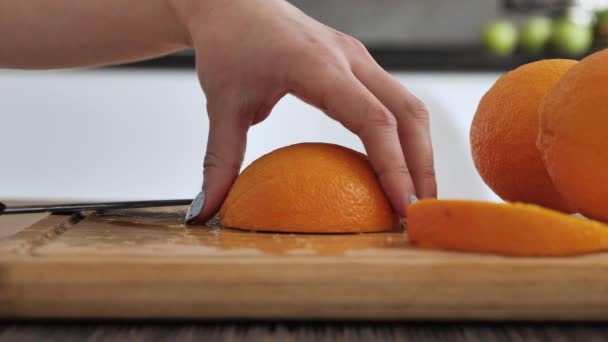Γυναίκα στην κουζίνα Κοπή με μαχαίρι ένα πορτοκάλι σε φρέσκα γλυκά και αρωματικά φέτες. — Αρχείο Βίντεο