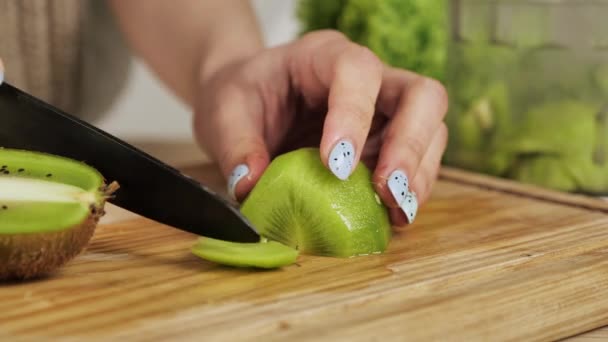 Primer plano de las manos de las mujeres cortando kiwi pelado fresco. Fruta para un desayuno familiar saludable — Vídeos de Stock