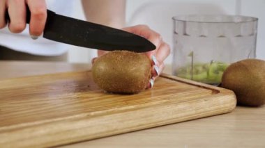 Kadın eli, kiviyi bir bıçakla ikiye böldü. Tahta bir tahtanın üzerinde. Kilo vermek için besin