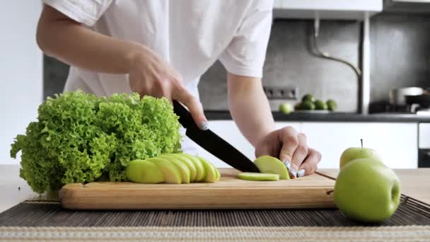 Femme cuisine des aliments sains dans la cuisine elle coupe tranchée pomme verte. — Video