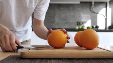 Tahta bir kesme tahtasının üzerinde turuncu kesen kadın elleri. Meyve doğrama.