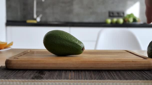 Eetlust, verse avocado ligt op een houten tablet. Gezond fitness eten in moderne keuken interieur — Stockvideo