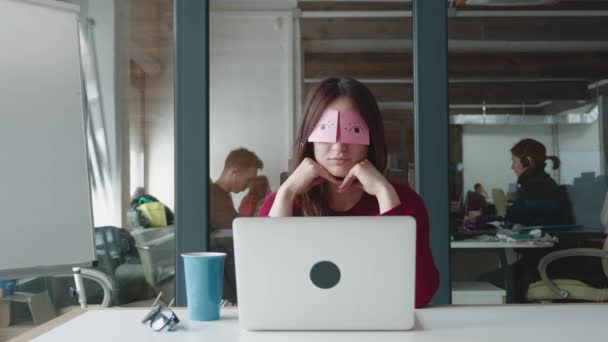 Bored female staff napping at workplace covering eyes with sticky notes. — Stock Video