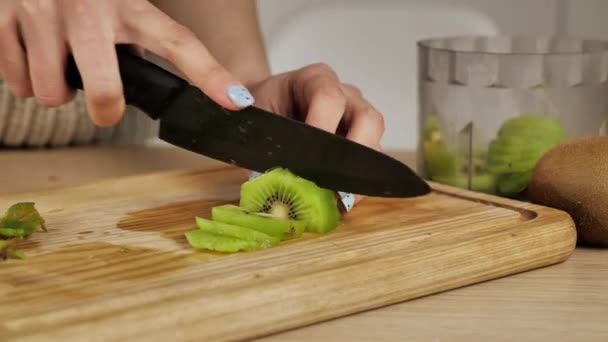 Frau schneidet die Kiwi auf einem Holzbrett in der Küche. Zutaten für gesunde Lebensmittel — Stockvideo