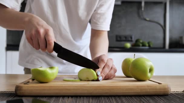 La muchacha que corta la manzana verde en los trozos a la tabla de bambú en la cocina. — Vídeos de Stock
