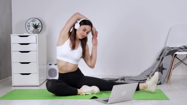 Passende ung trener på nettet som viser sidestilling ved hjelp av direktesendt strømvideo på laptop. Sportsinstruktør for positive kvinner som praktiserer yoga med klienten på avstand – stockvideo
