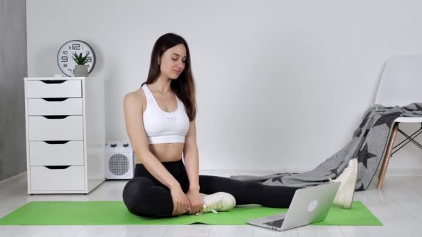 Junge Frau übt Meditation, telefoniert per Video mit Gruppenmitgliedern, winkt mit der Hand zum Laptop und lächelt — Stockvideo