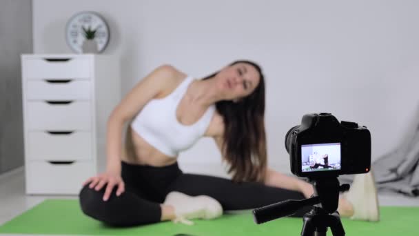 Mujer haciendo ejercicio, haciendo ejercicio de estiramiento en una esterilla de yoga y dispara vídeo en línea en la cámara en casa. Inclinación lateral — Vídeo de stock