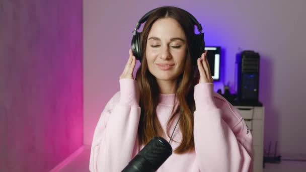 Aufgeregte Frau hört Musik über Kopfhörer im Neon-Hintergrund — Stockvideo