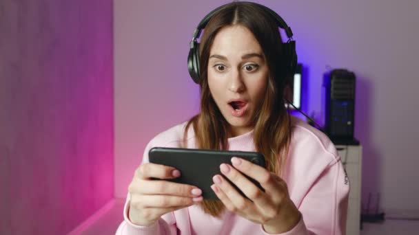 Estilo de vida mujer joven en auriculares jugar juego y está perplejo — Vídeo de stock