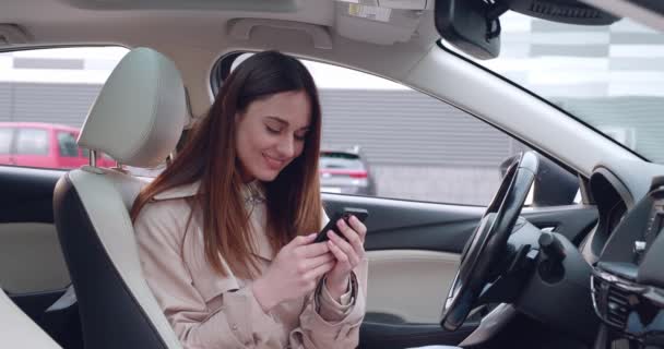 Retrato de mujer joven usando su Smartphone en el coche. Empresaria está revisando correos, chats mientras, sirviendo noticias. — Vídeos de Stock