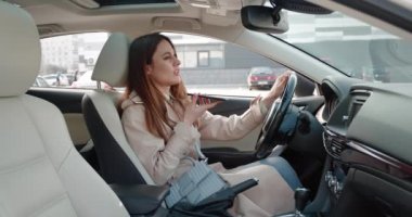 Uzun saçlı, kahverengi saçlı, bej ceketli, cep telefonunda sanal asistanı olan bir kadın. Gülümseyen beyaz kadın arkadaş veya kullanım için sosyal ağda sesli mesajla cevap veriyor