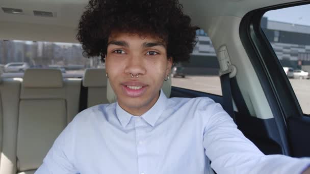 Retrato de alegre millennial afro-americano homem falando vídeo chat acenando mão dentro moderno carro sorridente saudação — Vídeo de Stock