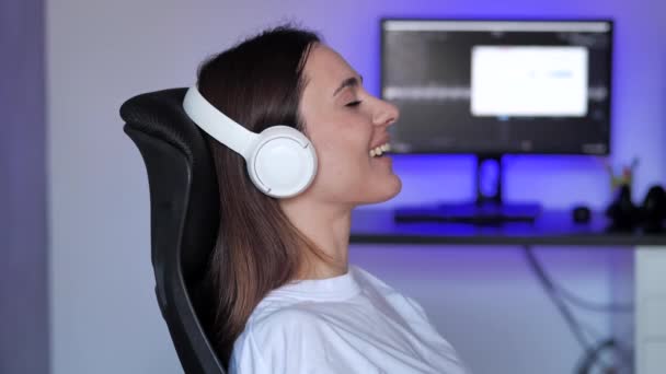 Young caucasian woman relaxing on comfortable armchair with eyes closed using wireless earphones. Pretty lady enjoys listening chill music audio sound meditating and dreaming at home — Stock Video