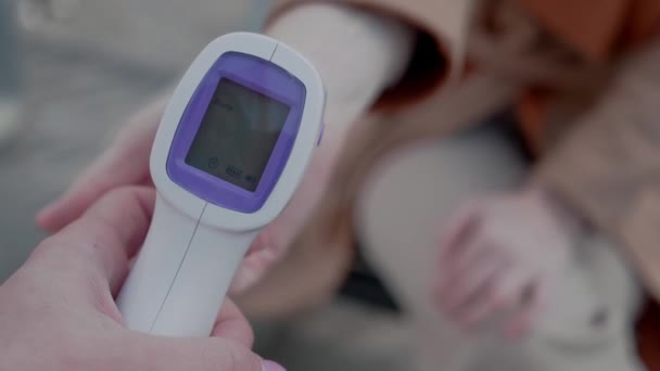 医生测量病人的体温，并在红外非接触式温度计的显示屏上显示正常温度 — 图库视频影像