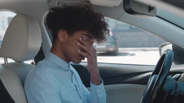Joven afroamericano, sentado dentro del coche está muy molesto y estresado — Vídeos de Stock