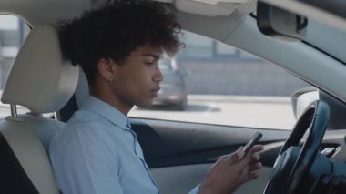 Lüks arabalardaki başarıyı kutlayan mutlu Afrikalı Amerikalı işadamı. Yakışıklı melez adam akıllı telefondan iyi haberler okuyor..