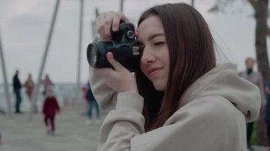 Güzel milenyum kadın fotoğrafçısı fotoğraf çekiyor, odaklanıyor, kamera çekimin amacını seçiyor, ekran görüntüsünü gösteriyor, fotoşop, 4k kameralı kadın. Yan görünüm