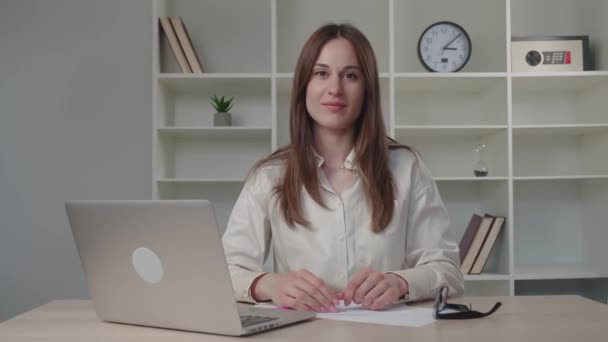 Sorrindo bela mulher de negócios milenar sentado à mesa olhando para a câmera, segurando câmera web zoom chamada conversa distante com os colegas. Profissional blogueiro feminino gravação de vídeo. — Vídeo de Stock