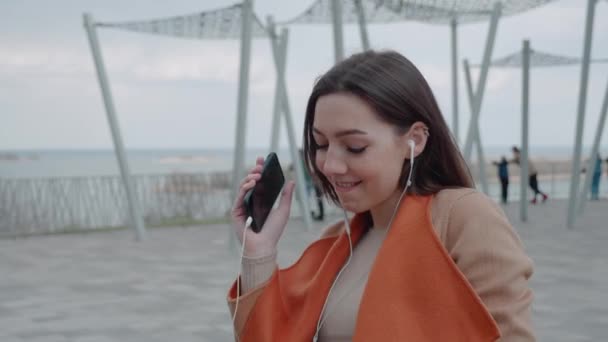 Moderna joven urbana atractiva mujer escuchando música con auriculares al aire libre — Vídeos de Stock