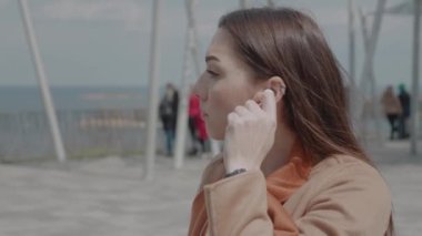 Kulaklıklı, mutlu genç bir kadının şehirde tek başına eğlenmesi. Neşeli, çekici, esmer, tasasız, müzik dinleyen kadın.